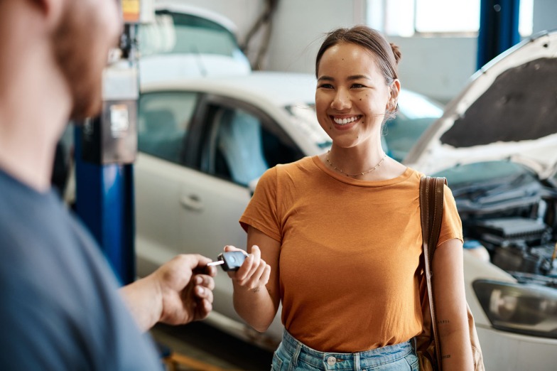 customer and auto repair technician exchange a car key and a friendly smile